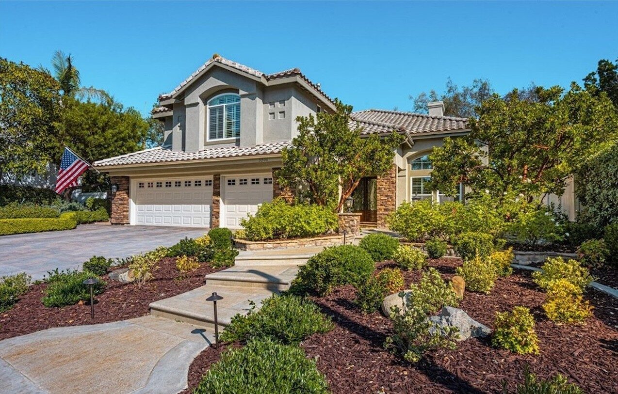Two-story single-family home with a tile roof and landscaped entry in San Clemente