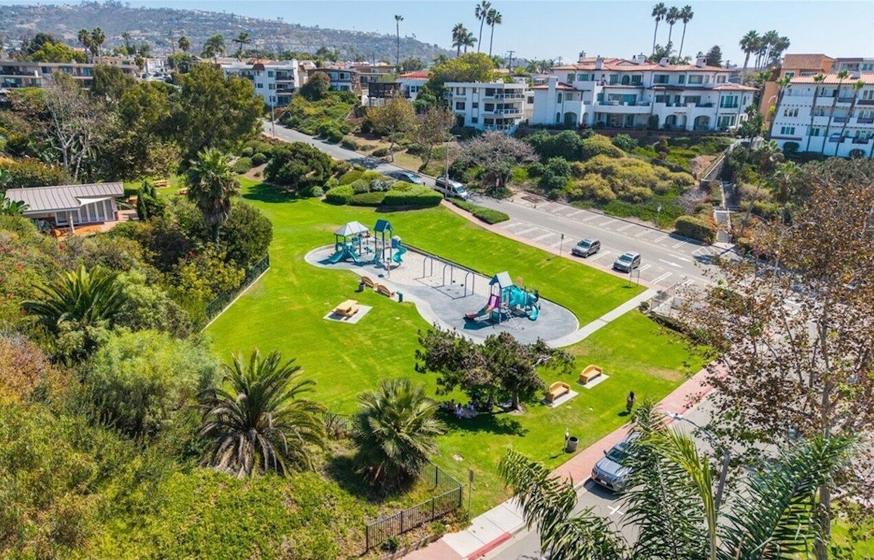 Aerial view of a neighborhood park with two playgrounds, picnic tables and lawn above the street in San Clemente