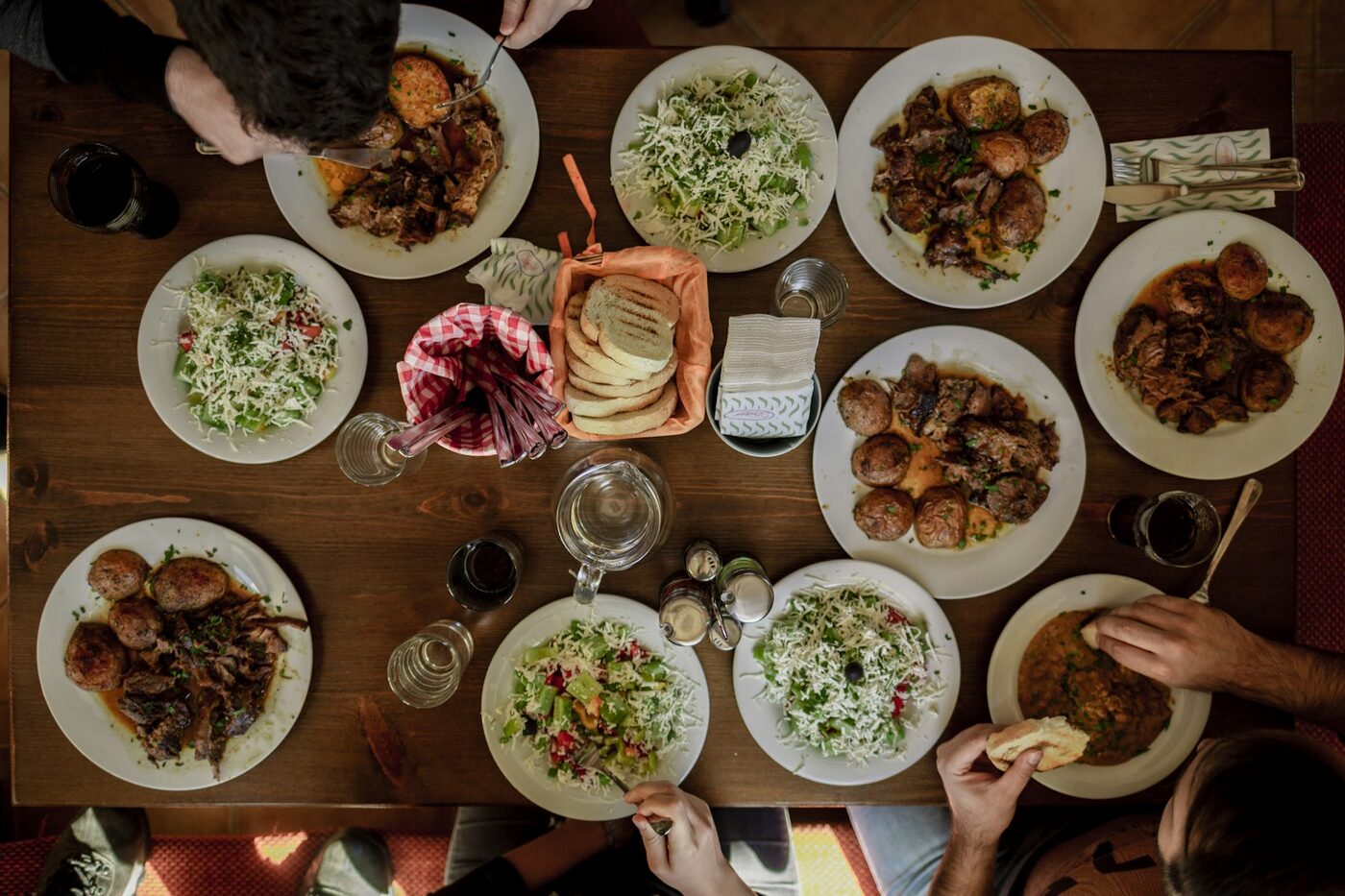 Overhead view of a shared dinner table with plates of food and people eating