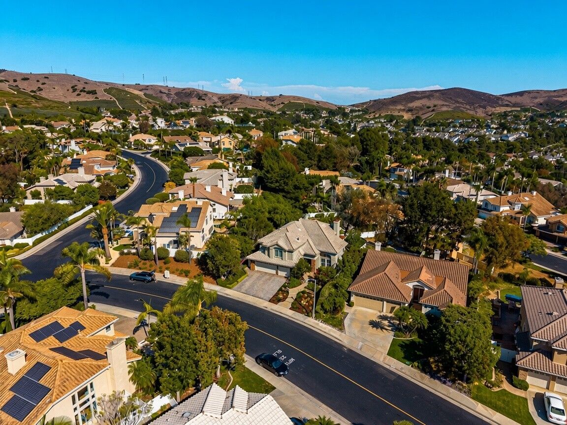 Aerial view of homes along a curving street with rolling hills behind
