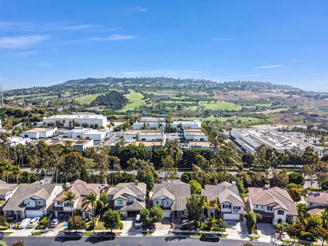 Aerial view of a row of two-story homes in Talega with a golf course and hills behind