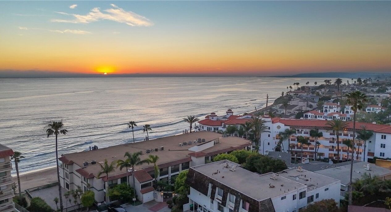 Sunset over the Pacific beside oceanfront buildings with red tile roofs