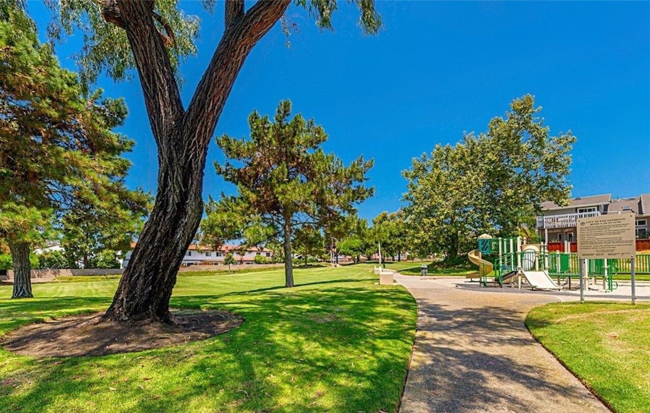 Neighborhood park in San Clemente with mature trees, a walking path and a playground
