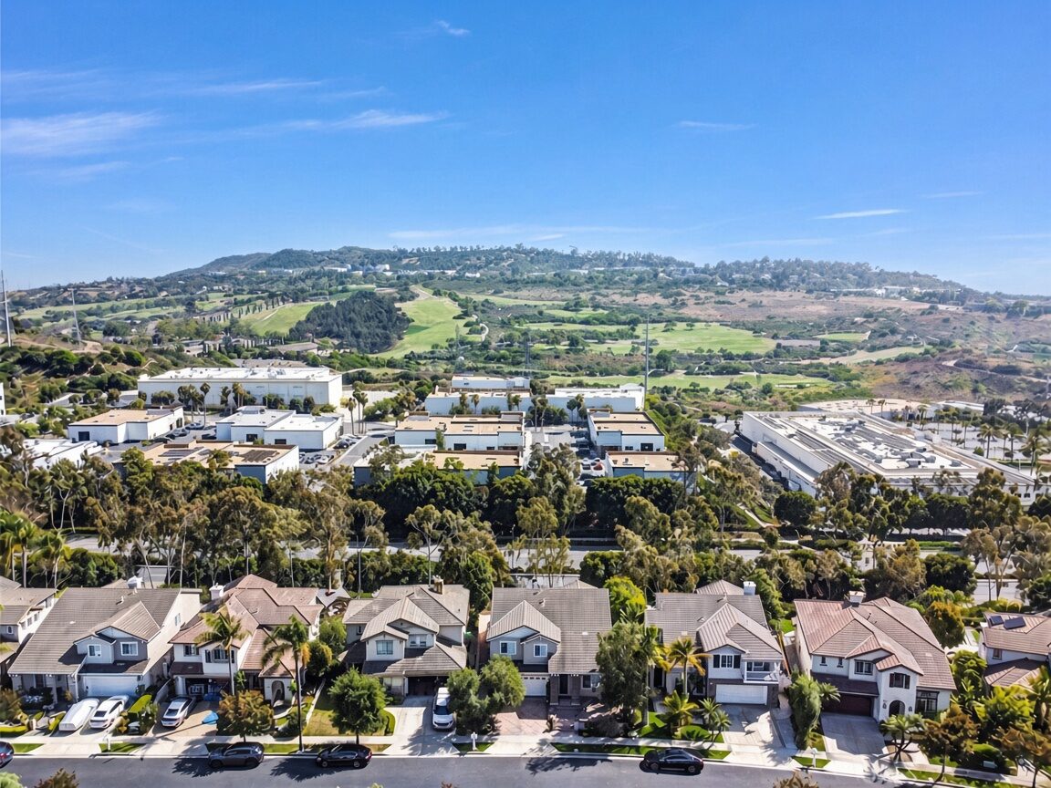 Aerial view of a row of two-story homes in Talega, San Clemente, with a golf course and rolling hills behind